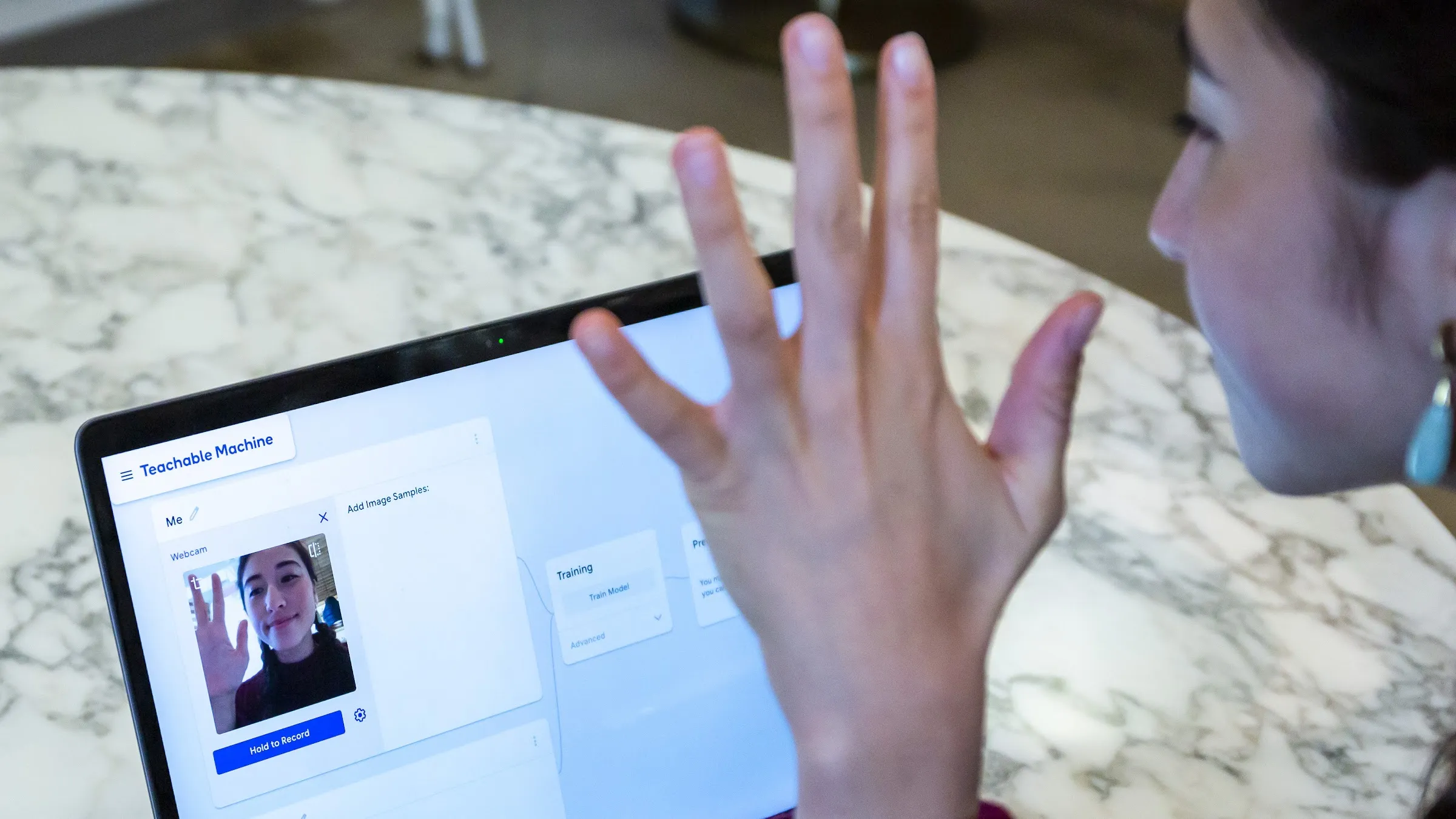 A person trains a model with their webcam in Teachable Machine, an experiment by Google Creative Lab, Google PAIR, Use All Five, and Støj (2017). Image from [teachablemachine.withgoogle.com](https://teachablemachine.withgoogle.com/).